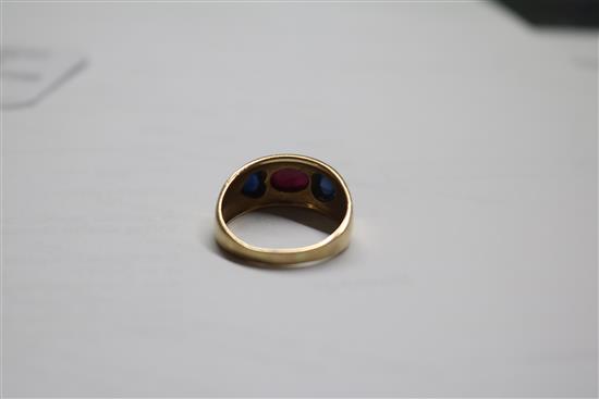 A yellow metal, cabochon ruby and sapphire three stone dress ring, size R.